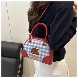 Close-up of cute plaid canvas boston bag featuring a red apple patch and leather handles