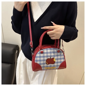 Detail of red and blue checkered mini crossbody bag with apple print and red leather handles
