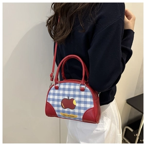 Model wearing the plaid mini Boston bag with red leather trim and apple pattern