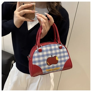 Detail shot of a plaid Boston handbag with red leather trim and apple embroidery
