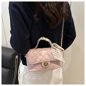 Detail of pink quilted chain bag with silk scarf handle and golden twist lock closure