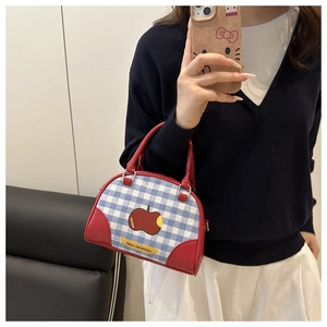 Detail of red and blue checkered handbag with apple print and stylish red leather handles