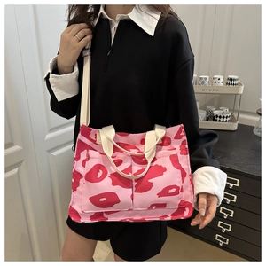 Gros plan d'un sac bandoulière en toile rose avec doubles poches et motif camouflage