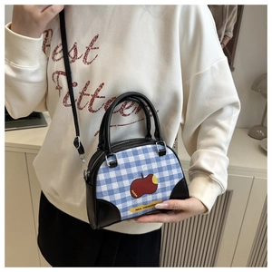 Detail view of the cute apple patch and blue checkered fabric on this trendy crossbody bag