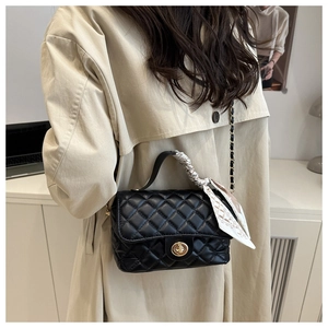 Close-up of black quilted leather handbag with gold twist lock and scarf handle detail