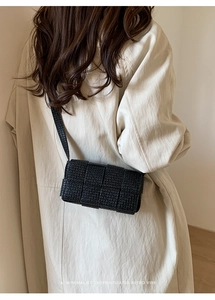Modern black woven leather shoulder bag with minimalist retro vibe on white background