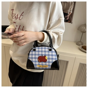Close-up of blue gingham bowling bag with red apple print and black leather accents