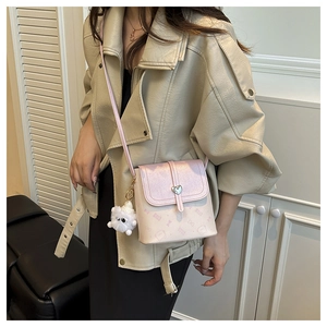Detail of pink and white crossbody bucket bag with heart lock and plush charm
