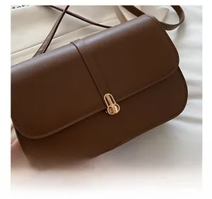 Close-up of brown leather shoulder bag featuring a fine grain texture and gold metal clasp