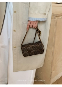 Detail of a dark brown woven handbag with a geometric pattern and long shoulder strap