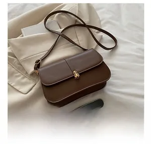 Close-up of brown leather bag with golden twist-lock buckle and vertical strap detail