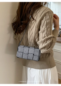 Detail of black and white checkered woven bag with sparkling rhinestone texture and slim strap