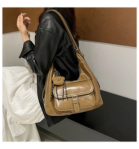 Detail of vintage brown oil wax leather tote bag with contrast stitching and teddy charm