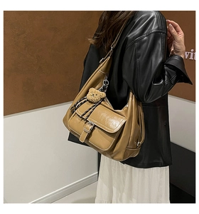 Detail of glossy caramel brown patent leather tote bag with a plush bear charm on the strap