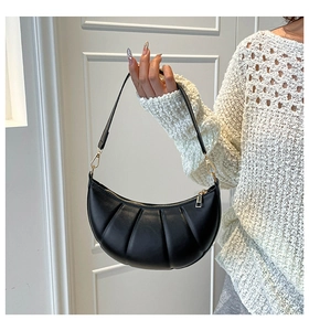 Detail of black croissant crescent bag showing vertical pleated texture and gold hardware