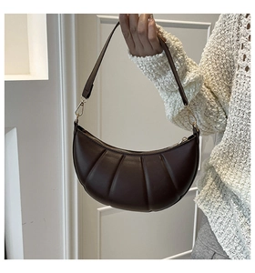 Detail view of a dark brown crescent bag with pleated leather texture and gold hardware