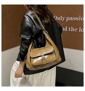 Close-up of vintage brown glossy leather hobo bag featuring decorative flap pocket detail
