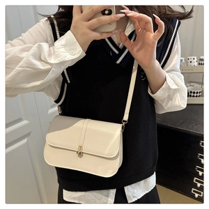 Mirror selfie showing a minimalist off-white baguette bag with a gold twist lock