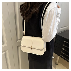 Side view of model wearing a minimalist beige PU leather baguette bag with gold metal buckle