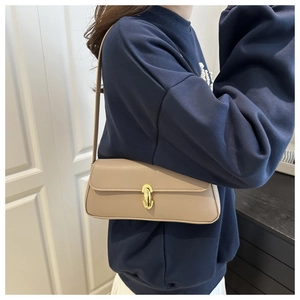 Detail of light brown pebble leather shoulder bag featuring a gold oval twist lock