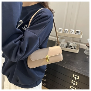 Detail view of the elegant beige lychee leather underarm bag with gold rotating lock
