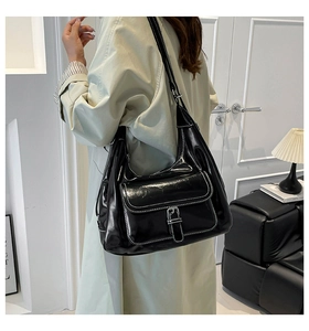 Detail of retro glossy black shoulder bag with white contrast stitching and silver buckle