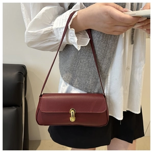 Detailed macro of the wine red litchi grain texture and gold oval clasp on the shoulder bag
