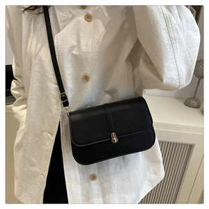 Close-up of black leather baguette bag featuring a gold twist lock and smooth texture