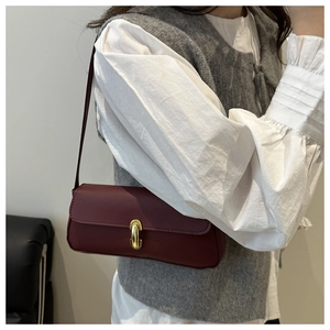 Close-up of burgundy baguette bag featuring pebbled leather and gold oval metal lock