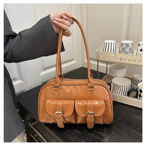 Detailed view of brown glossy patent leather bowling bag with two buckle front pockets