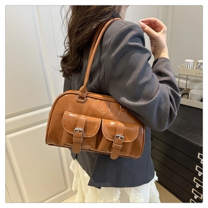 Close-up of vintage brown gloss leather shoulder bag featuring decorative silver buckles