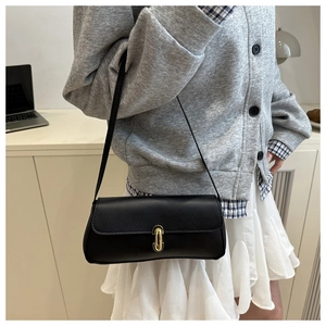 Close-up of black pebble leather underarm bag with an elegant golden oval metal clasp
