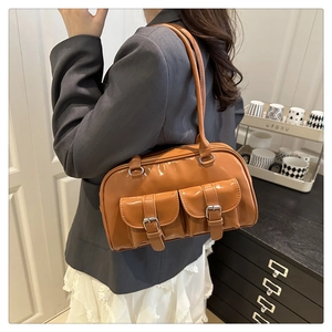 Close-up of brown patent leather Boston bag featuring dual front pockets and metal buckles