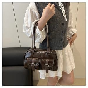 Detail of dark brown glossy patent leather boston bag with silver buckles on front pockets