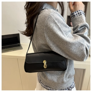Detail of black lychee-textured leather shoulder bag with elegant gold U-shaped metal buckle