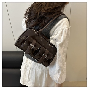 Detail view of dark brown patent leather Boston bag with double front buckle pockets