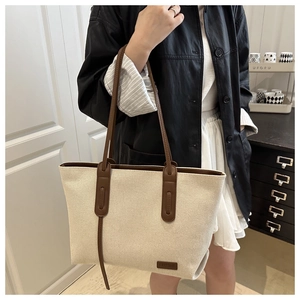 Dettaglio macro della toppa in pelle su borsa tote in tela bianca e bordo marrone