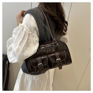 Detail of glossy brown patent leather shoulder bag with silver hardware and pockets