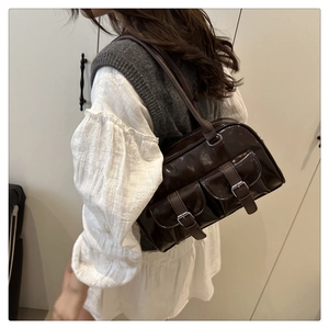 Detail of glossy brown faux leather shoulder bag featuring vintage front buckle pockets