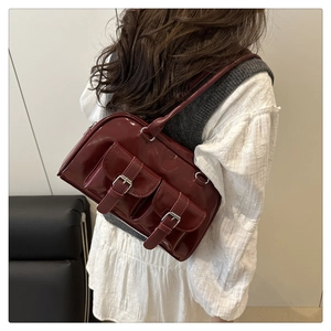 Detail of dark red glossy patent leather shoulder bag with vintage dual buckle pockets