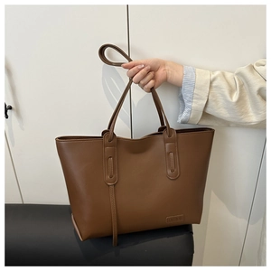 Dettaglio della borsa tote in pelle PU marrone con manici lunghi e targhetta fashion