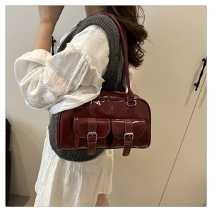 Close-up of vintage dark burgundy patent leather shoulder bag with buckle pockets
