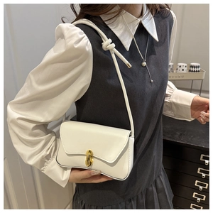 Sac bandoulière blanc chic avec boucle dorée et nœud, porté par un mannequin en extérieur