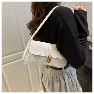 Détail du sac sous l'aisselle blanc motif crocodile avec fermoir doré sur modèle