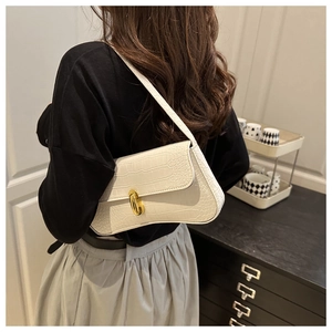 Detail of white crocodile pattern baguette bag with gold metal buckle on shoulder