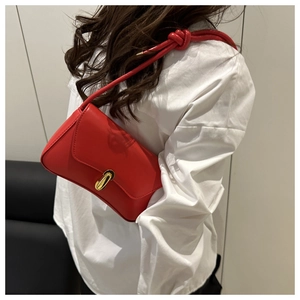 Detail showing red leather underarm bag with gold metal clasp on model's shoulder