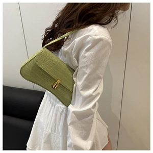 Detail of light green crocodile embossed faux leather shoulder bag with gold metal clasp