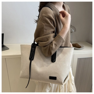 Detail of minimalist cream canvas tote bag with black leather straps and fashion label