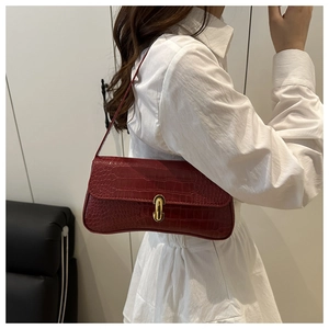 Détail du sac baguette bordeaux à motif crocodile et boucle métallique dorée en forme de U
