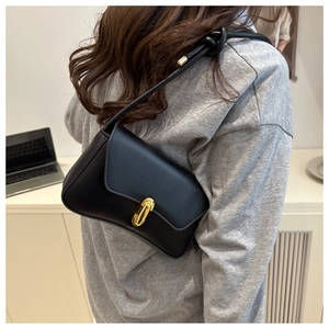 Détail du sac sous le bras en cuir noir avec fermoir doré et bandoulière à nœud décoratif